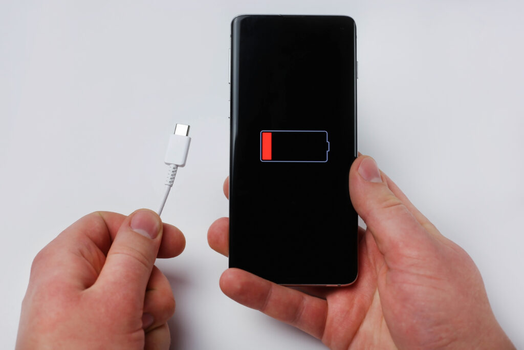 holds charging cable smartphone showing low battery